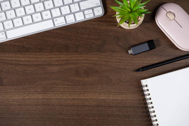 istock organized workspace with keyboard, notebook, pen, flash drive, plant, and wireless mouse on wooden desk. top view 2190577789