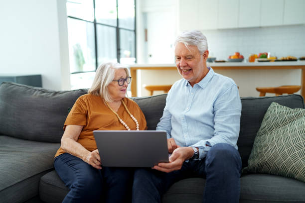 istock Smiling senior couple using laptop while relaxing on a sofa at home 2190578393