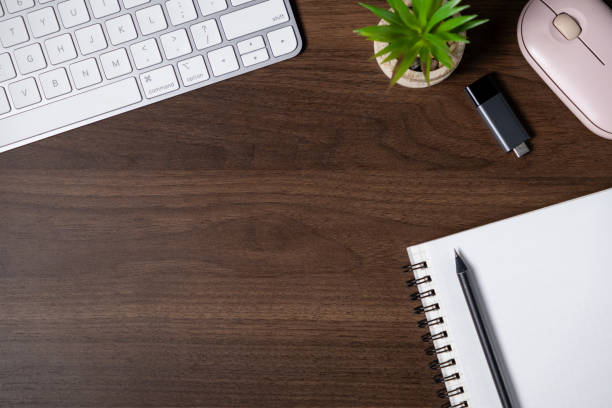 istock organized workspace with notebook, pen, keyboard, USB flash drive, plant, and mouse on a wooden desk. top view 2190578496