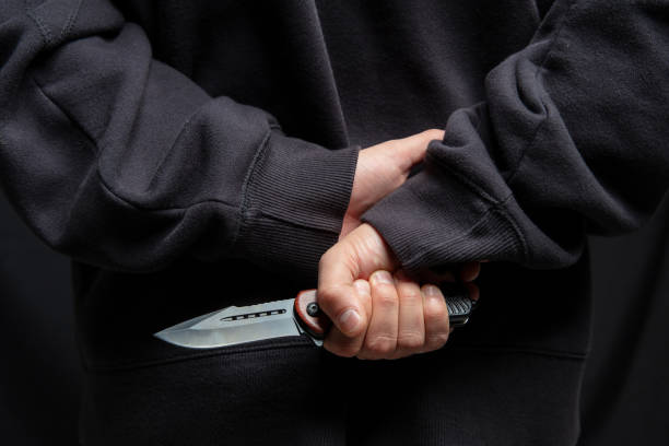 istock Robber hiding a knife behind his back, man holding a weapon in hand closeup 2190582565