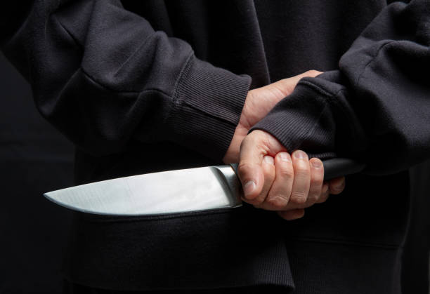istock Robber hiding a knife behind his back, man holding a weapon in hand closeup 2190582566