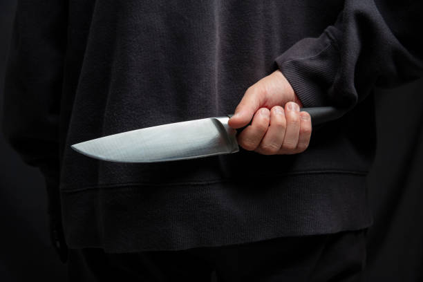 istock Robber hiding a knife behind his back, man holding a weapon in hand closeup 2190582572