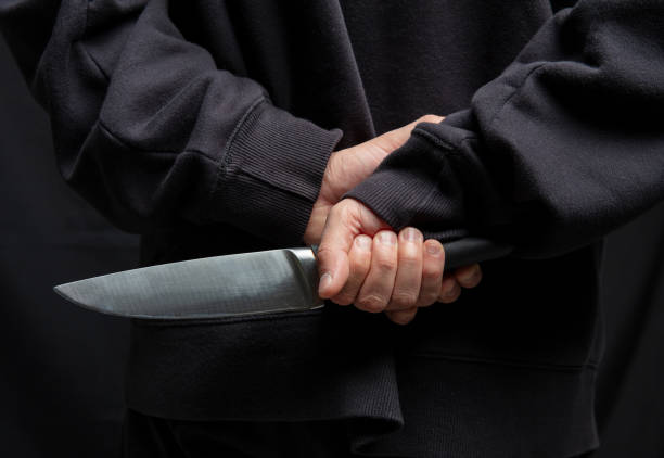 istock Robber hiding a knife behind his back, man holding a weapon in hand closeup 2190582573