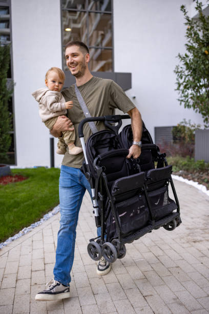istock Dad carrying his baby in one arm and a folded stroller in the other 2190588049