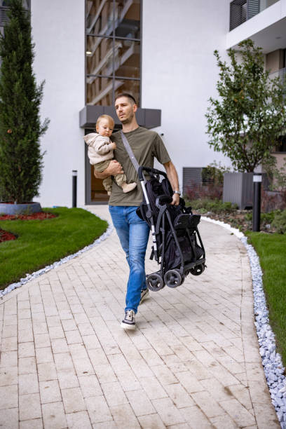 Young man carrying his child and stroller with pride and purpose in modern area
