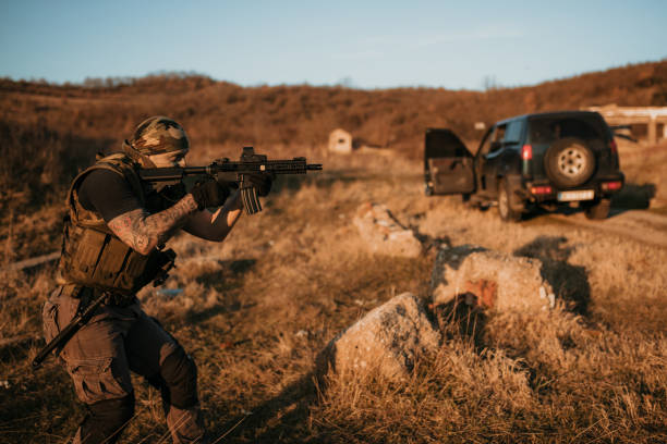 istock Armed Tactical Operator Outdoors Engaging in Training Activity Near Off-Road Vehicle 2190589011