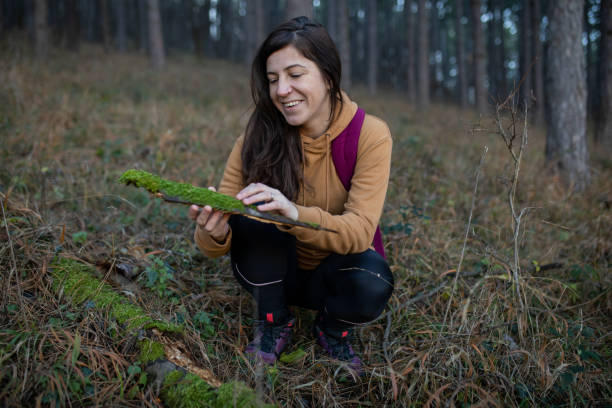 istock Young smiling woman is crouching down in the forest and holding moss. 2190590919