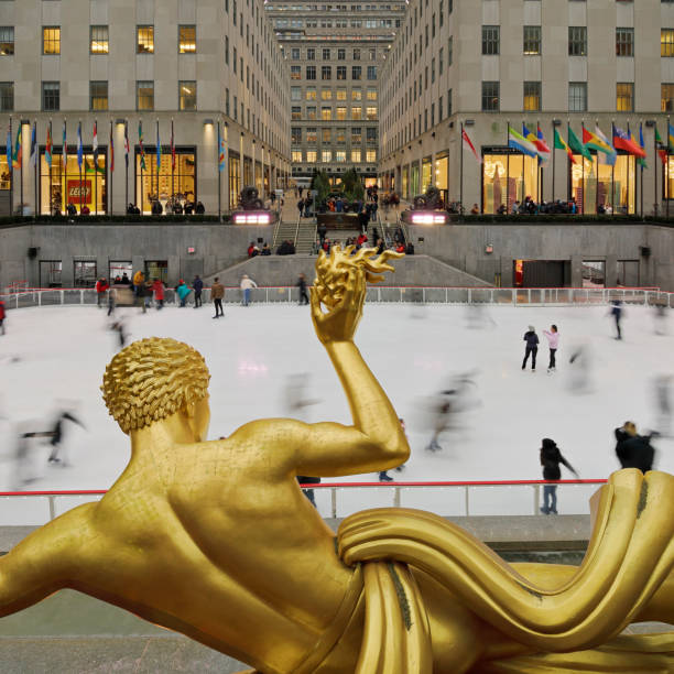 New York City, USA - January 28, 2020: Ice skaters in the Rockefeller Center’s lower plaza  housing the ice skating rink and the Bronze sculpture of Prometheus (c.1934).