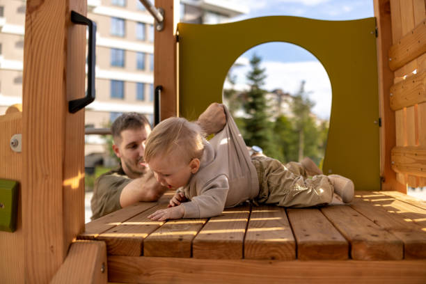istock Father helping son to climb on wooden slide 2190593415