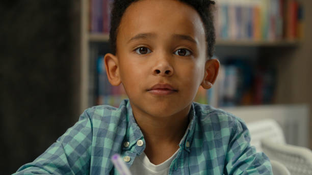 istock Little boy kid son African American ethnic child concentrated study learn write homework classroom lesson prepare task elementary school education student schoolboy studying drawing writing at desk 2190596291