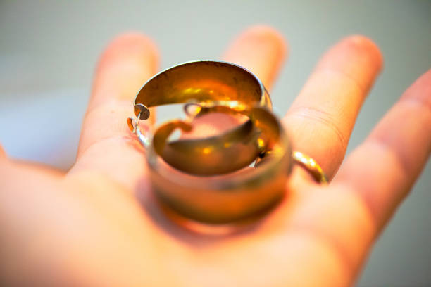 A close-up photo captures a man's hands delicately holding golden circular earrings, showcasing elegance and style.
