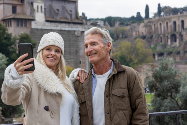Mature couple take selfie above forum grounds and Palatine Hill, Rome