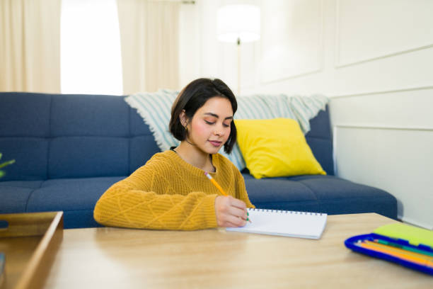 istock Young creative female sketching designs in notebook while relaxing on living room floor 2190600452