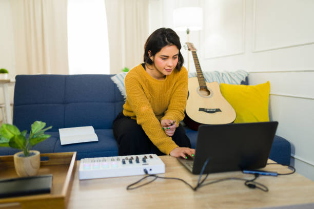 istock Female musician composing music using laptop, midi controller, acoustic guitar in home recording workspace 2190600664