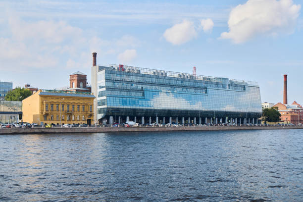 Riverside development in St. Petersburg showcases modern buildings by the water, blending urban design with nature under cloudy skies.
