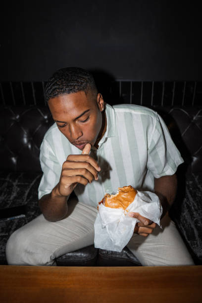 istock Young man enjoying a delicious burger in a restaurant 2190604564
