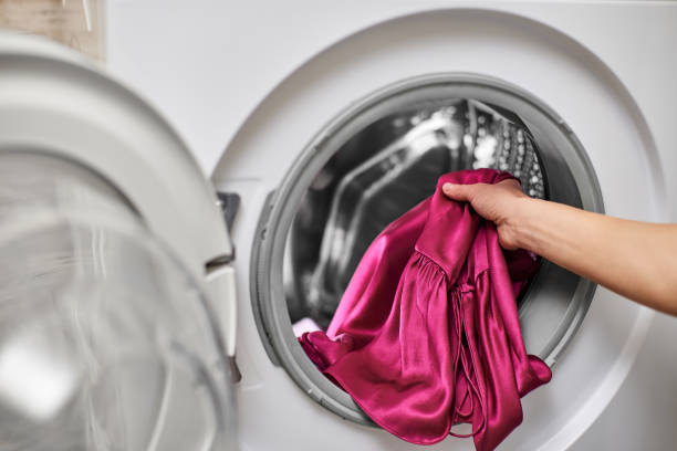 istock Woman putting clothes into the washing machine 2190606137