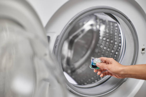 istock hand putting laundry detergent capsule into washing machine 2190606141
