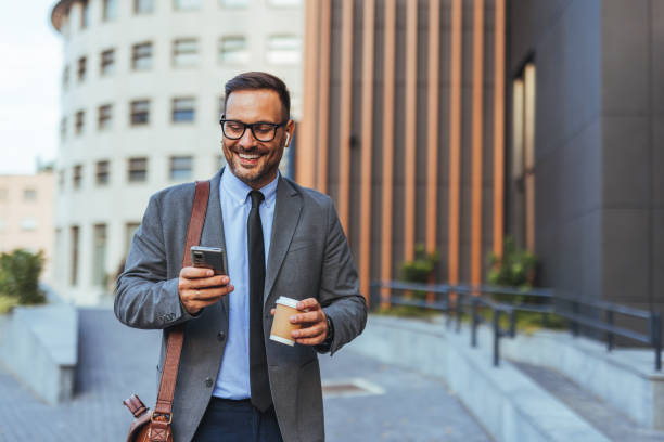 istock Confident Businessman Enjoying Coffee and Checking Smartphone Outdoors 2190606598
