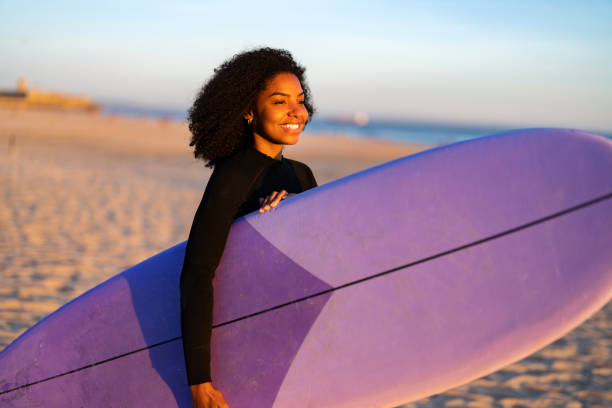 istock Joyful Black Female Surfer with Board on Beach 2190607299