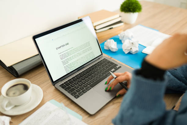 Female writer working on novel, typing manuscript at home office desk, enjoying coffee while pausing from creative process