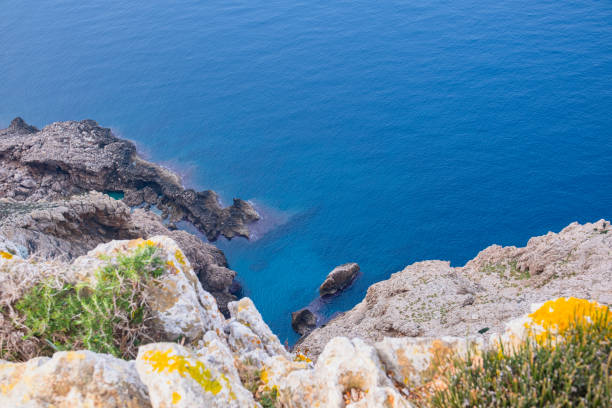 High cliffs jutting out far into the sea. Beautiful seascape. Calm blue sea and clear sky above huge cliffs.