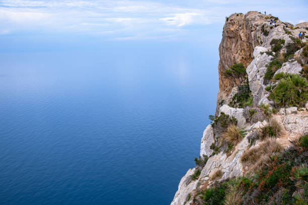 High cliffs jutting out far into the sea. Beautiful seascape. Calm blue sea and clear sky above huge cliffs.