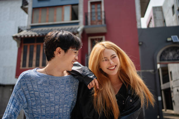 Two young friends smile as they walk in a city.
