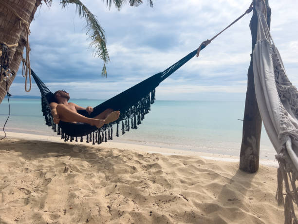 istock Relaxed Man Lounging in Hammock on Tropical Beach 2190620318