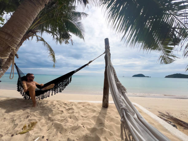 istock Relaxed Man Lounging in Hammock on Tropical Beach 2190620321