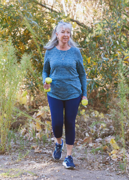 istock Senior woman walking with hand weights on a path 2190623669