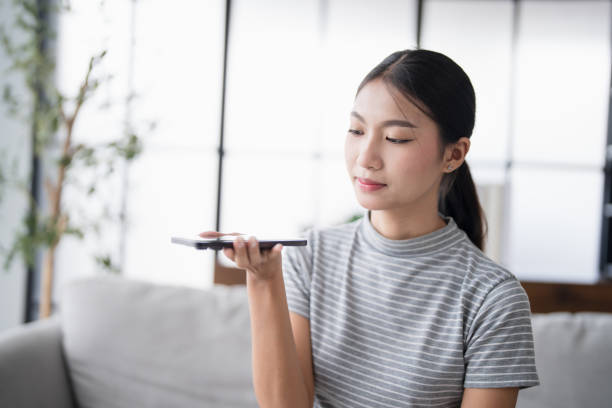 istock Asian woman using voice assistant on smartphone at home conversation with online assistantÂ Voice chat bot conversational AI Modern Technologies. 2190634196