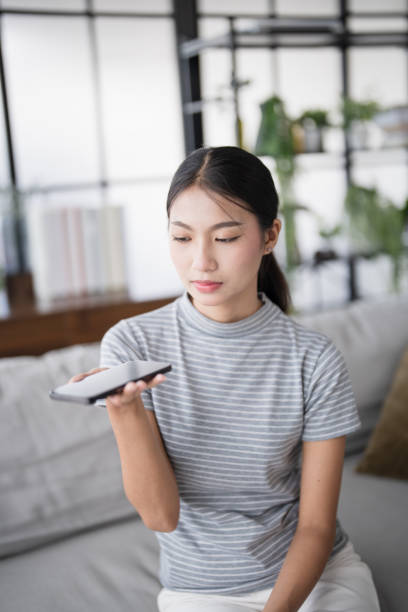 istock Asian woman using voice assistant on smartphone at home conversation with online assistantÂ Voice chat bot conversational AI Modern Technologies. 2190634220