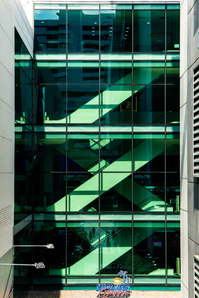 Bangkok, Thailand - 20 11 2025 : green-tinted glass wall in a building near Siam Square, internal staircase structure.