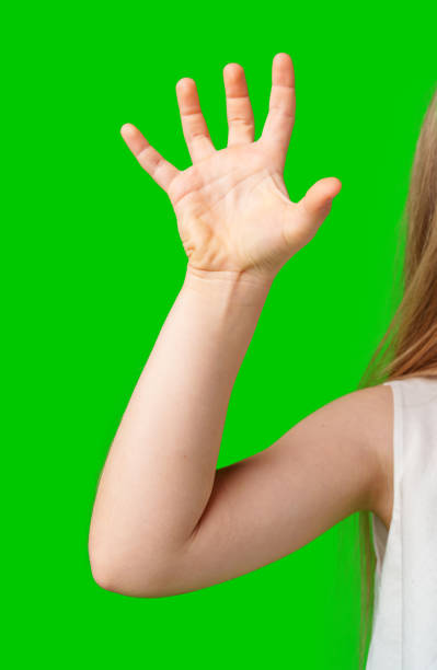 istock A child's hand raised in greeting against a bright green background 2190634971