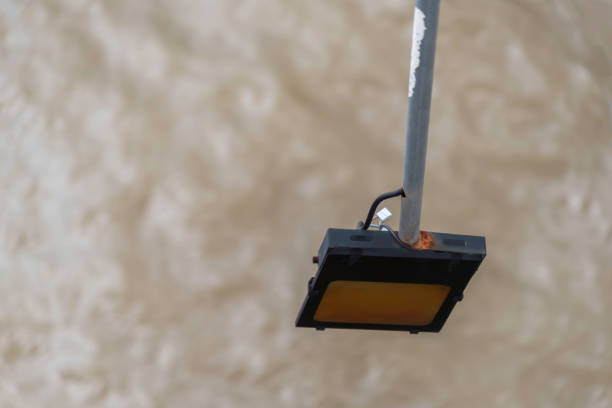 Mini photovoltaic or solar cell panel and floodlight led installed on metal pole against sunset