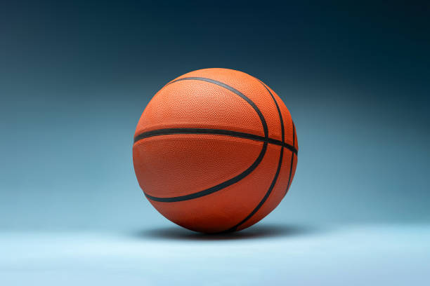 istock Orange basketball ball lit from above on blue background 2190636335