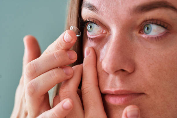 istock Young woman puts on soft contact lenses  into the eye, using lenses instead glasses for vision correction 2190636349