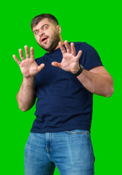 istock A man with a serious expression holds up both hands in a stopping gesture against a bright green background 2190636517