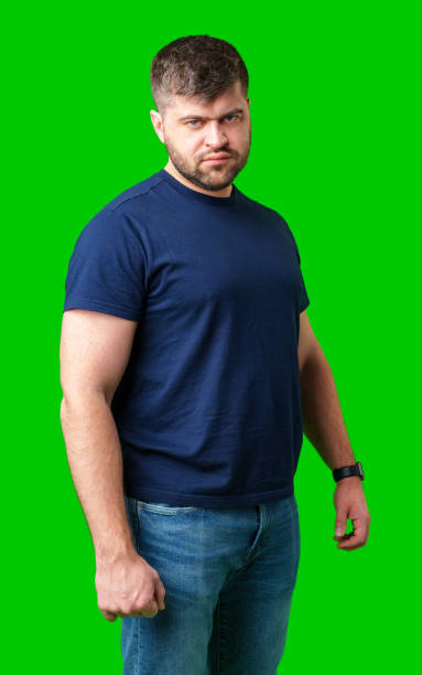 istock A determined young man stands confidently in casual attire against a bright green backdrop 2190636976