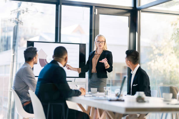 istock Young Professional Leading Business Presentation in Modern Office Setting with Attentive Colleagues 2190639115