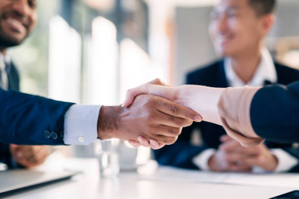 istock Professional Business Handshake in Modern Office Setting with Colleagues Smiling in the Background 2190639136
