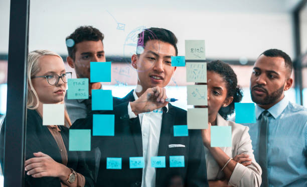 istock Team Discussing Business Strategy With Sticky Notes on Glass Board in Office Environment 2190640363