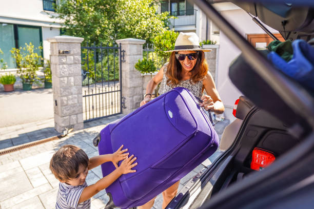 Mother and son loading luggage into car trunk for summer vacation