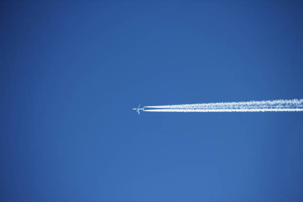 A plane flying high in the sky and making cloudscape behind it