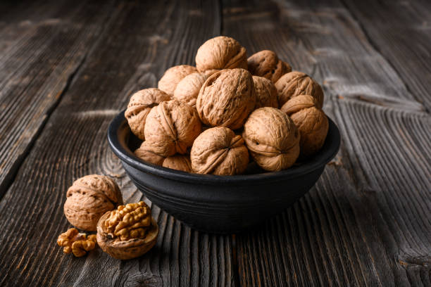istock Walnut nuts on black bowl on wooden table 2190646684