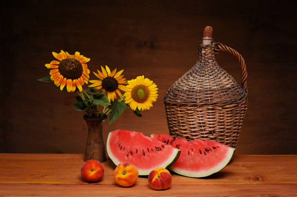 Still life, watermelon, sunflower, wicker balloon and peach on a wooden table