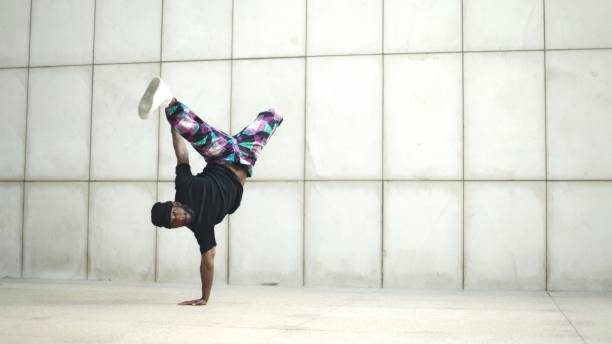 istock Breakdancer doing a handstand with legs spread in front of white wall 2190650509