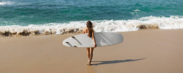 istock Woman Walking with Surfboard Toward the Ocean on a Sunny Beach 2190650549