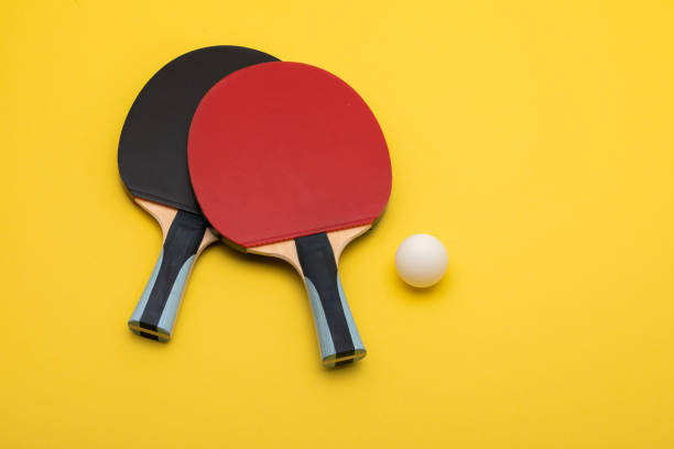 istock Professional Ping Pong Paddles with Ball on Vibrant Yellow Background 2190653814